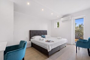 Ein Schlafzimmer mit einem Bett, zwei Stühlen, einem Fenster und einer Klimaanlage.