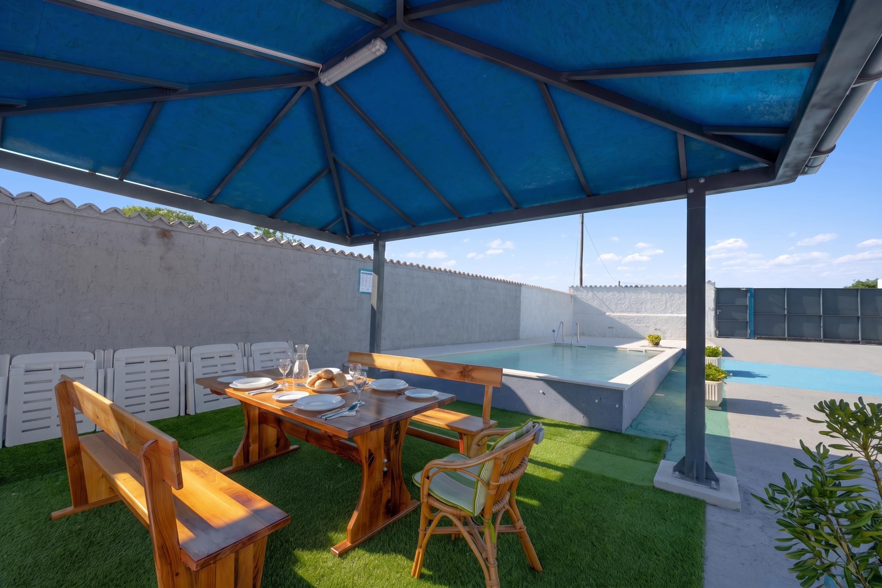 An outdoor patio with a wooden table, chairs, and a blue umbrella.
