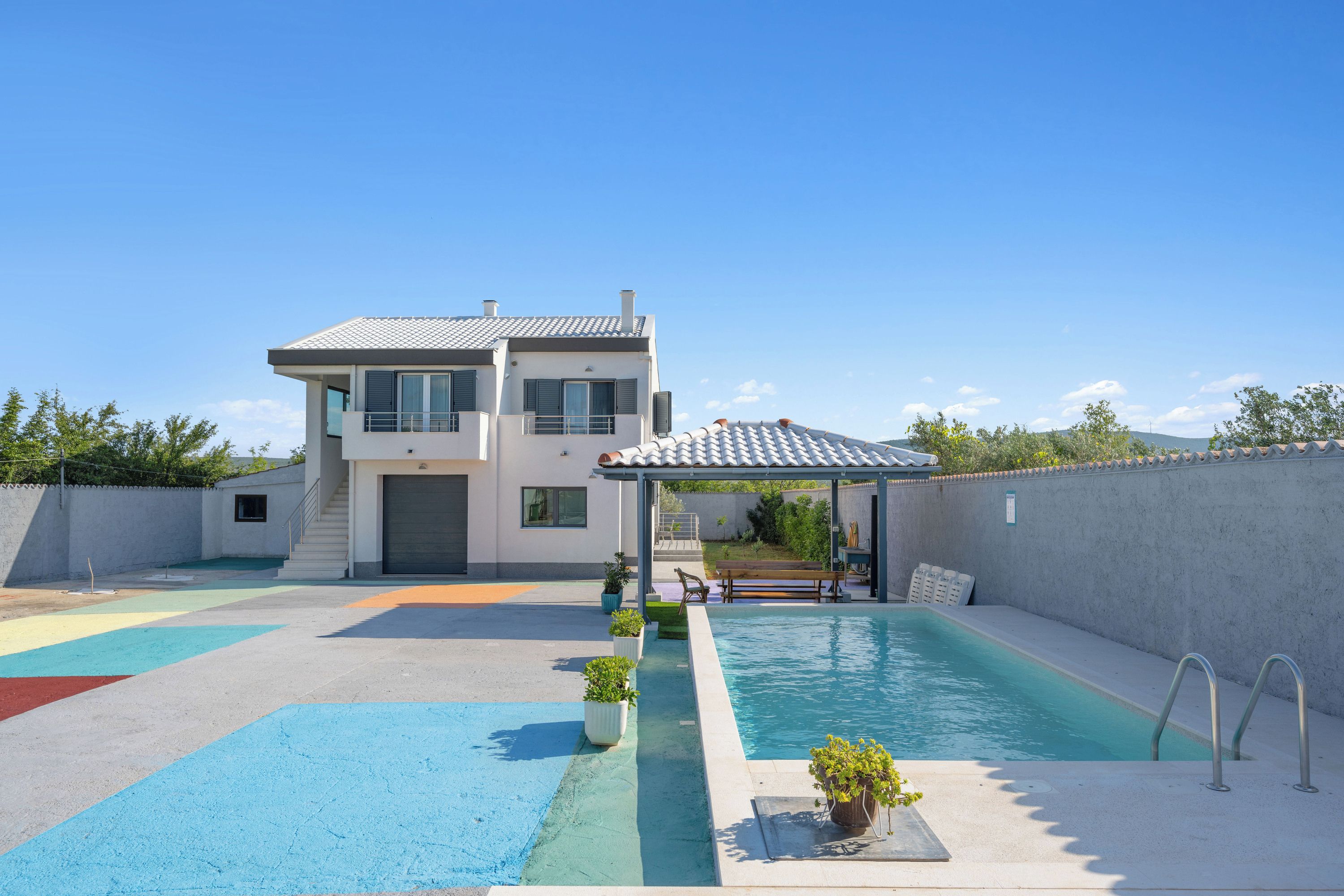 A modern two-story house with a swimming pool, a covered patio, and a fenced yard.