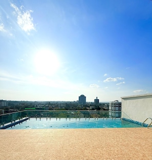 A rooftop pool with a cityscape view, a clear sky, and a distant building. - west suites studios nairobi west (Nairobi)