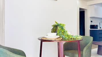 Een eethoek met een ronde tafel, twee stoelen, een plant in pot en twee ingelijste foto's aan de muur.