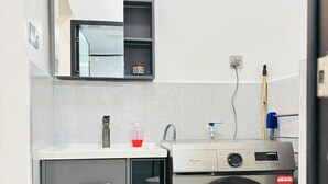 Ett litet och praktiskt tvättrum med tvättmaskin, ett litet skåp och en tvättho.