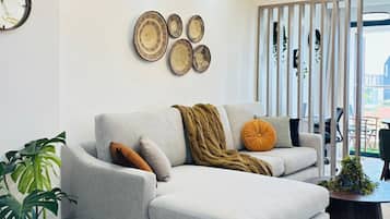 Una sala de estar moderna con un sofá seccional gris, un reloj de pared redondo y decoración mural.