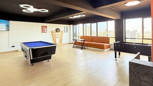 A spacious room with a pool table, a sofa, and a foosball table. - west suites studios nairobi west (Nairobi)