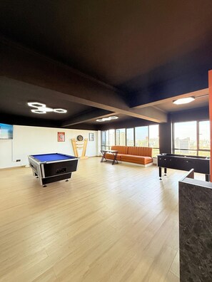 A spacious room with a pool table, a sofa, and a foosball table. - west suites studios nairobi west (Nairobi)