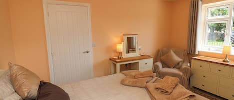 Une chambre à coucher avec un lit, une chaise, une commode, un miroir et une fenêtre.