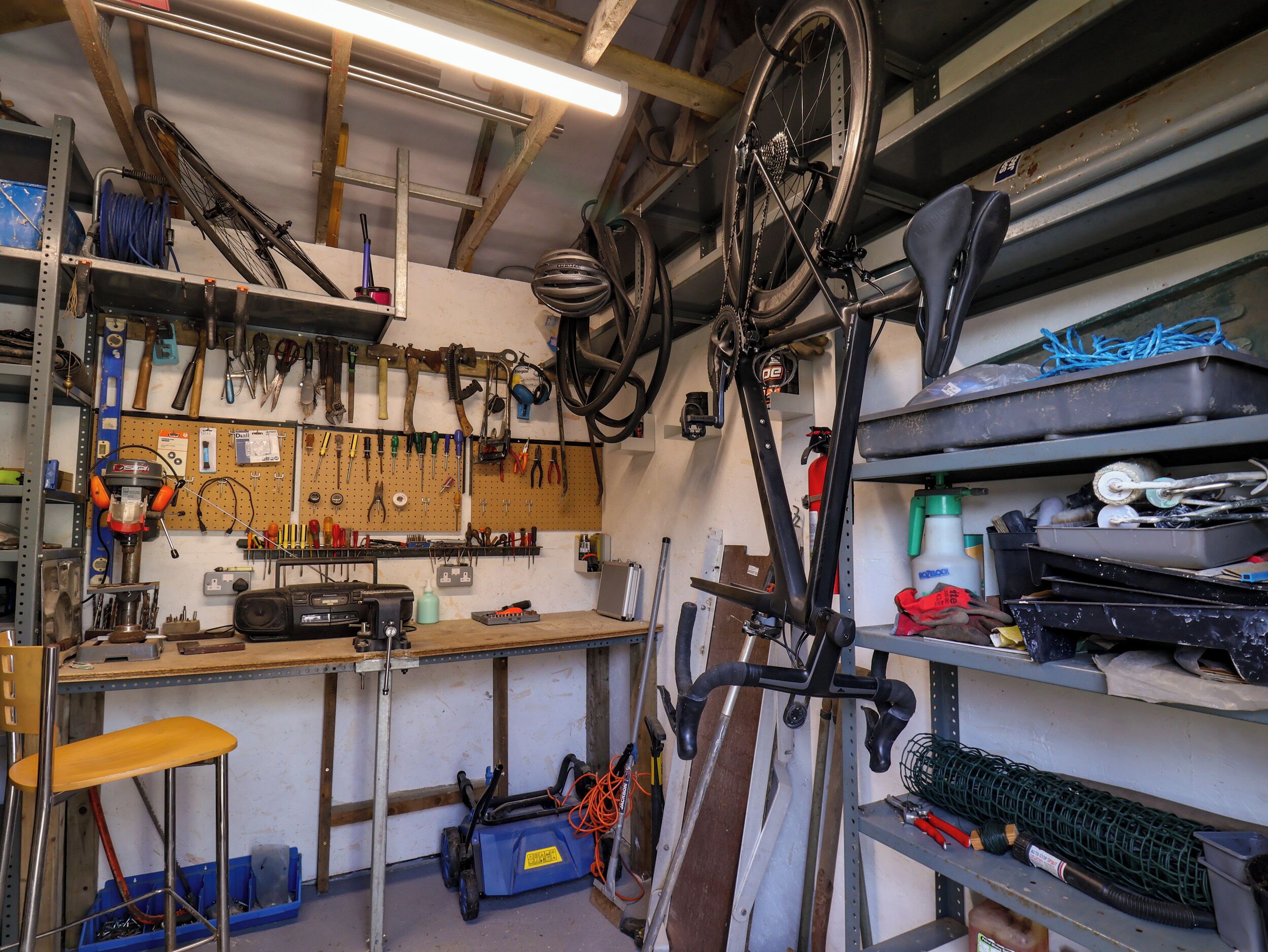 Een werkplaats met gereedschap, een fiets en een werkbank.