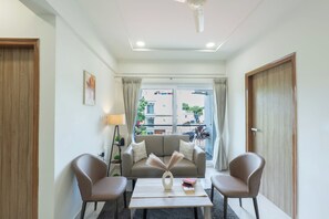 Un salon moderne avec un canapé, deux fauteuils, une table basse et une vue sur l’extérieur.
