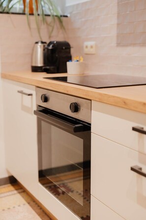 Eine Küche mit Backofen, Kaffeemaschine und einer Pflanze.