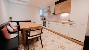 Eine moderne Küche mit Holztisch und -stühlen, weißen Schränken und einem gemusterten Boden.