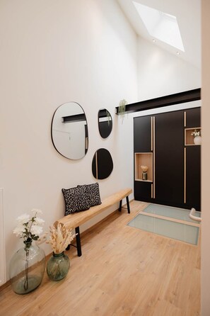 A modern interior with a bench, mirrors, and a black wardrobe. - 26 Pas de la Place (Gerpinnes)