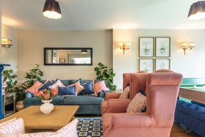 A living room with a sofa, armchair, coffee table, and a pool table.