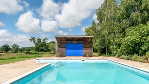 Une piscine dotée d’une structure en bois et d’une porte bleue.
