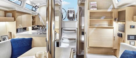 A compact, well-lit interior with a kitchenette, seating area, and a view through a door.