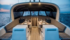 Ein Bootsdeck mit Essbereich, gepolsterten Sitzgelegenheiten und Blick auf das Wasser.