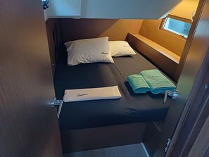 A compact cabin with a single bed, a small window, and a door.