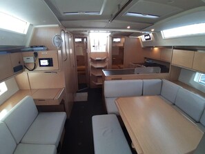 A compact interior with seating, a small kitchenette, and a control panel. - Sun-Kissed Sailing Adventure in Phuket (Mai Khao)