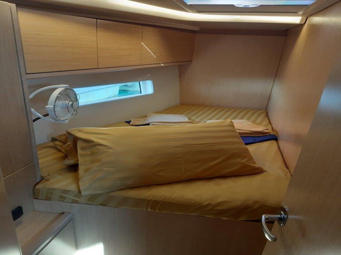 A compact travel room with a bed, storage cabinets, and a window.