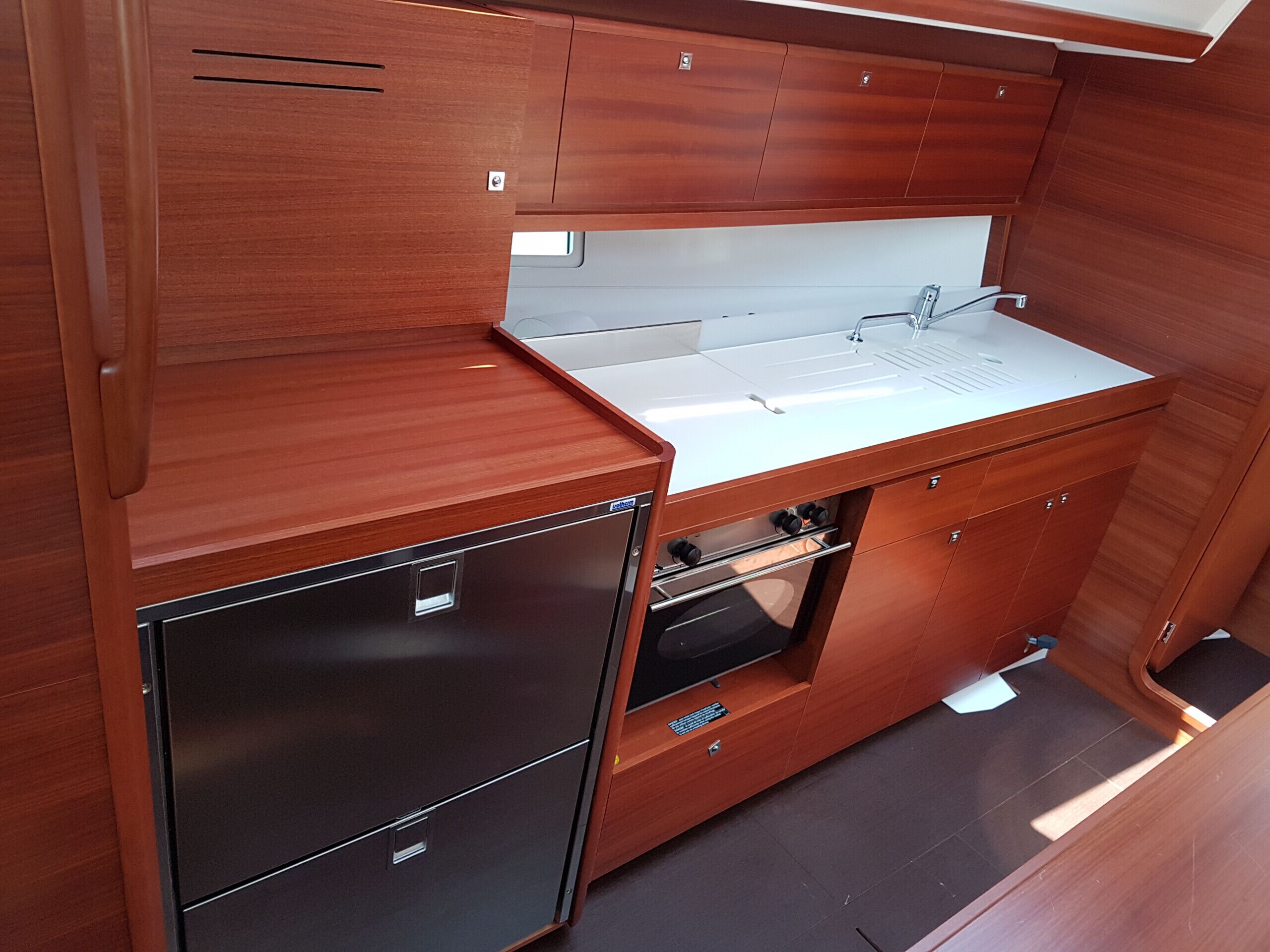 Eine kompakte Küche mit Holzschränken, einem Edelstahlkühlschrank und einem eingebauten Ofen.