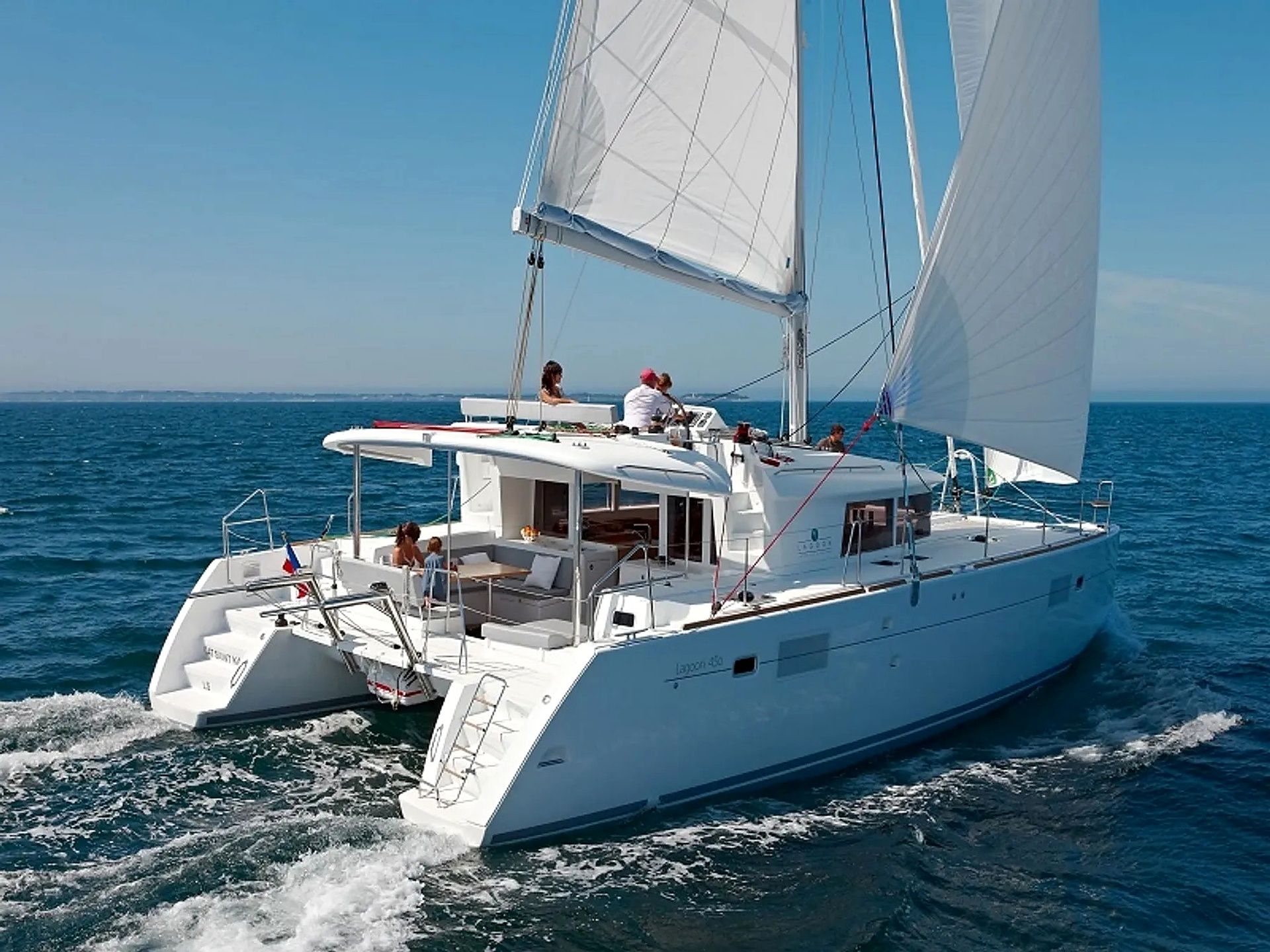 A white yacht with a spacious deck, multiple seating areas, and a visible cabin structure.
