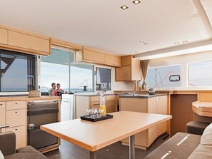 A modern kitchen with a dining area, large windows, and a view of the sea.