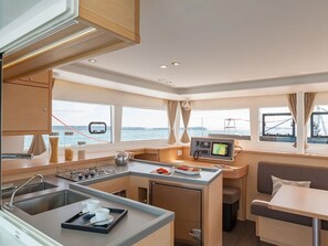A compact galley with a sink, stove, and a small dining area with a table and bench.