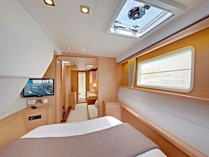 A modern interior with a bed, a television, a skylight, and a window.