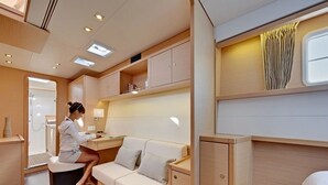 Um espaço interno compacto e bem iluminado, com um sofá, uma mesa pequena e um armário.