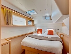 A compact, well-lit cabin with a bed, a small window, and a skylight.
