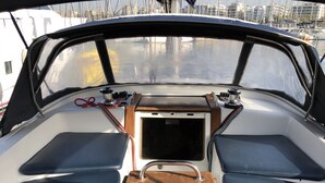 Das Deck eines Bootes mit einem Garmin Navigationsgerät, einem Holztisch und Sitzgelegenheiten.