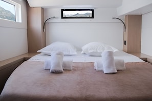 Habitación de hotel moderna con cama, dos almohadas, ventana y vista a las montañas.