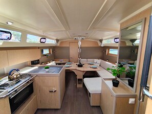 Una cocina compacta con estufa, lavamanos y zona de estar, que cuenta con una mesa central y monitores sobre ella.