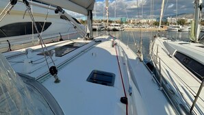 Un port esportiu amb diversos velers amarrats, cel serena i un paisatge urbà a la distància.