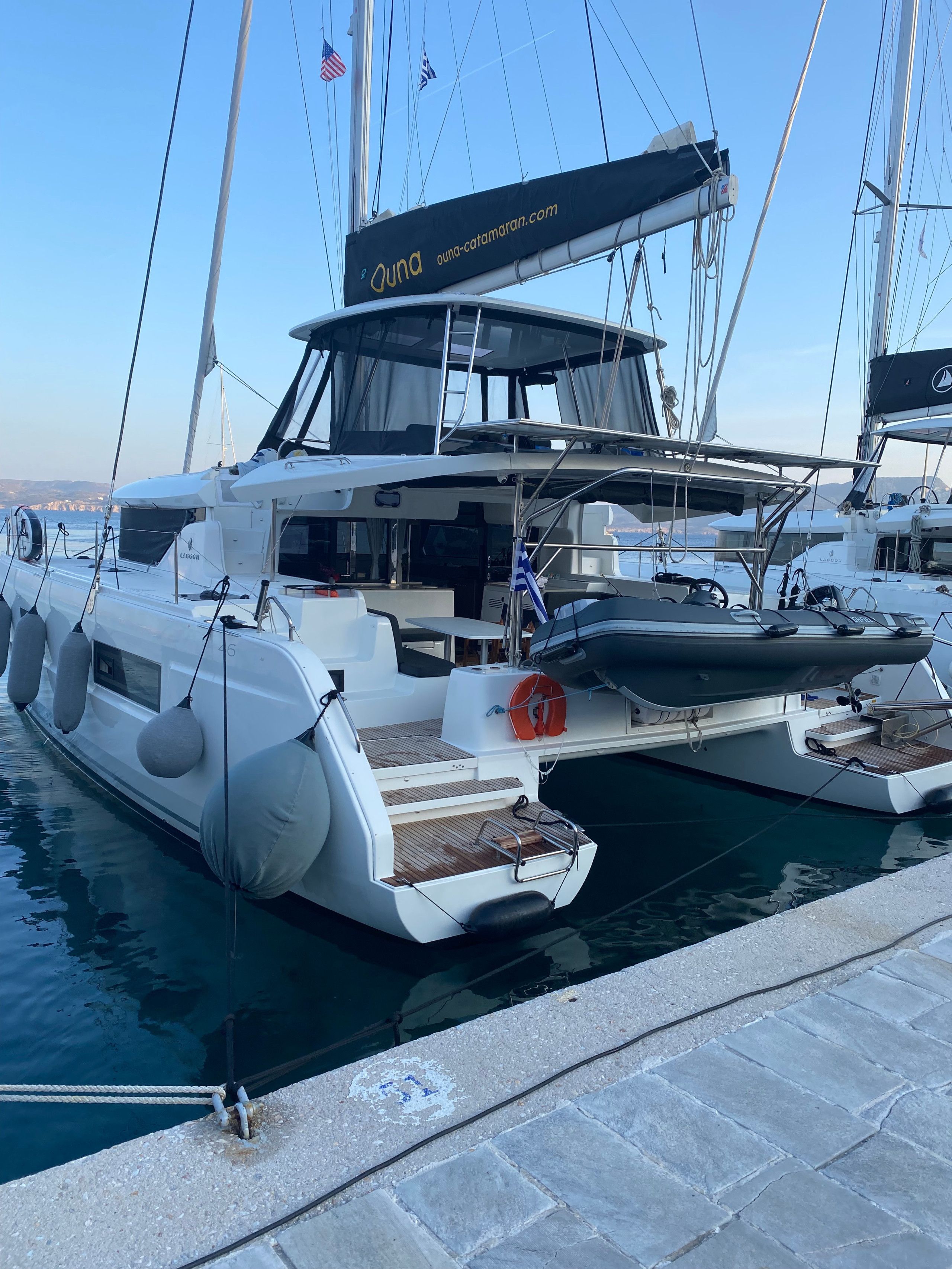 Uno yacht bianco ormeggiato in una marina, con un indirizzo web sullo scafo.