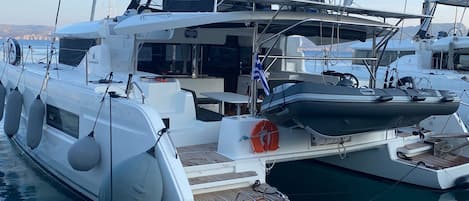 Un yate blanco amarrado en un puerto deportivo, con una dirección de sitio web en la cubierta.