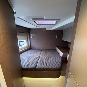 Ein kompaktes Wohnmobil-Interieur mit einem Bett, einem Dachfenster und einem kleinen Fenster.