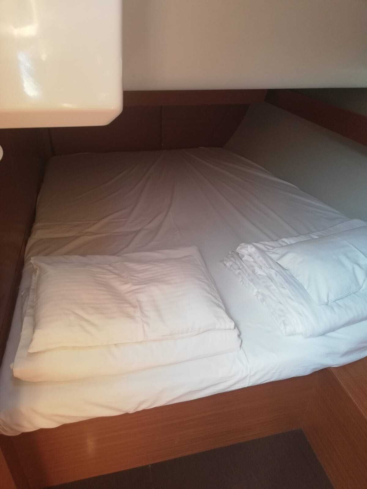 Ein Bett mit weißer Bettwäsche, einem Holz-Kopfteil und einem dunklen Boden.