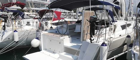 A marina with multiple sailboats docked, featuring a covered deck area, a steering wheel, and a visible website address.