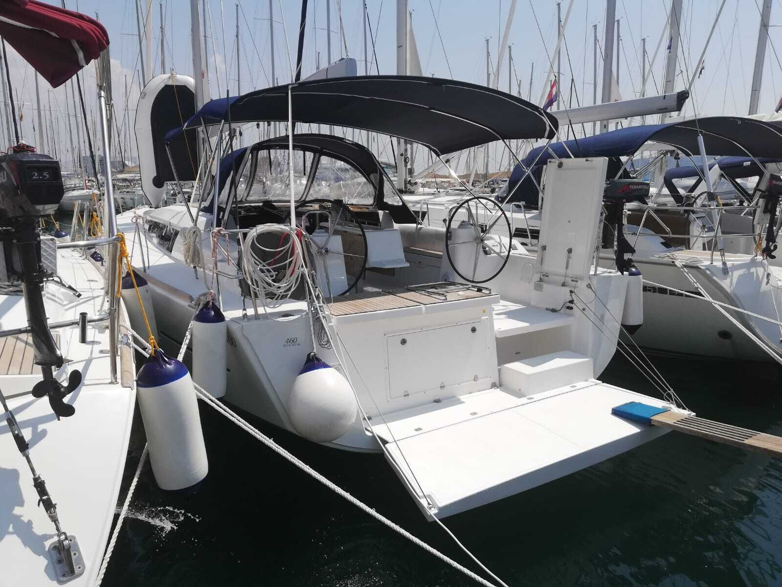 A marina with multiple sailboats docked, featuring a covered deck area with a steering wheel, winches, and life rings.
