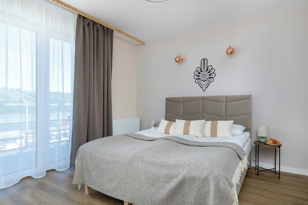 Bright studio apartment with a comfortable double bed, large windows, and modern décor.