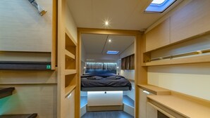 Een compacte, moderne kamer met een bed, ingebouwde opbergruimte en een dakraam.