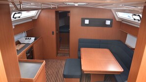 A compact RV interior with a dining area, a bench, a small kitchenette, and a window. - Sun-kissed Sailing Adventure in Split-Dalmatia, Croatia (Seget Donji)