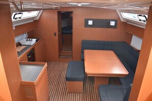 Ein kompaktes Wohnmobil-Interieur mit Essbereich, einer Sitzbank, einer kleinen Küchenzeile und einem Fenster.