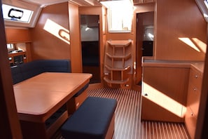 A compact interior with a dining table, bench, storage cabinets, and a control panel. - Sun-kissed Sailing Adventure in Split-Dalmatia, Croatia (Seget Donji)