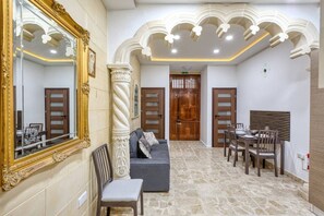 Eine Hotelhalle mit einem großen Spiegel, einer Couch, einem Essbereich und einer Treppe.