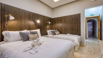 A hotel room with two beds, a wooden slat wall, and a hallway leading to an exit.