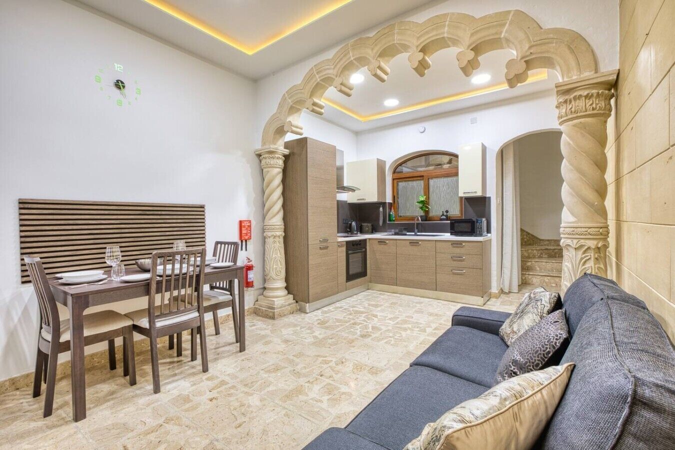 Sala de estar con sofá, mesa de comedor, sillas y una zona de cocina con armarios y microondas.