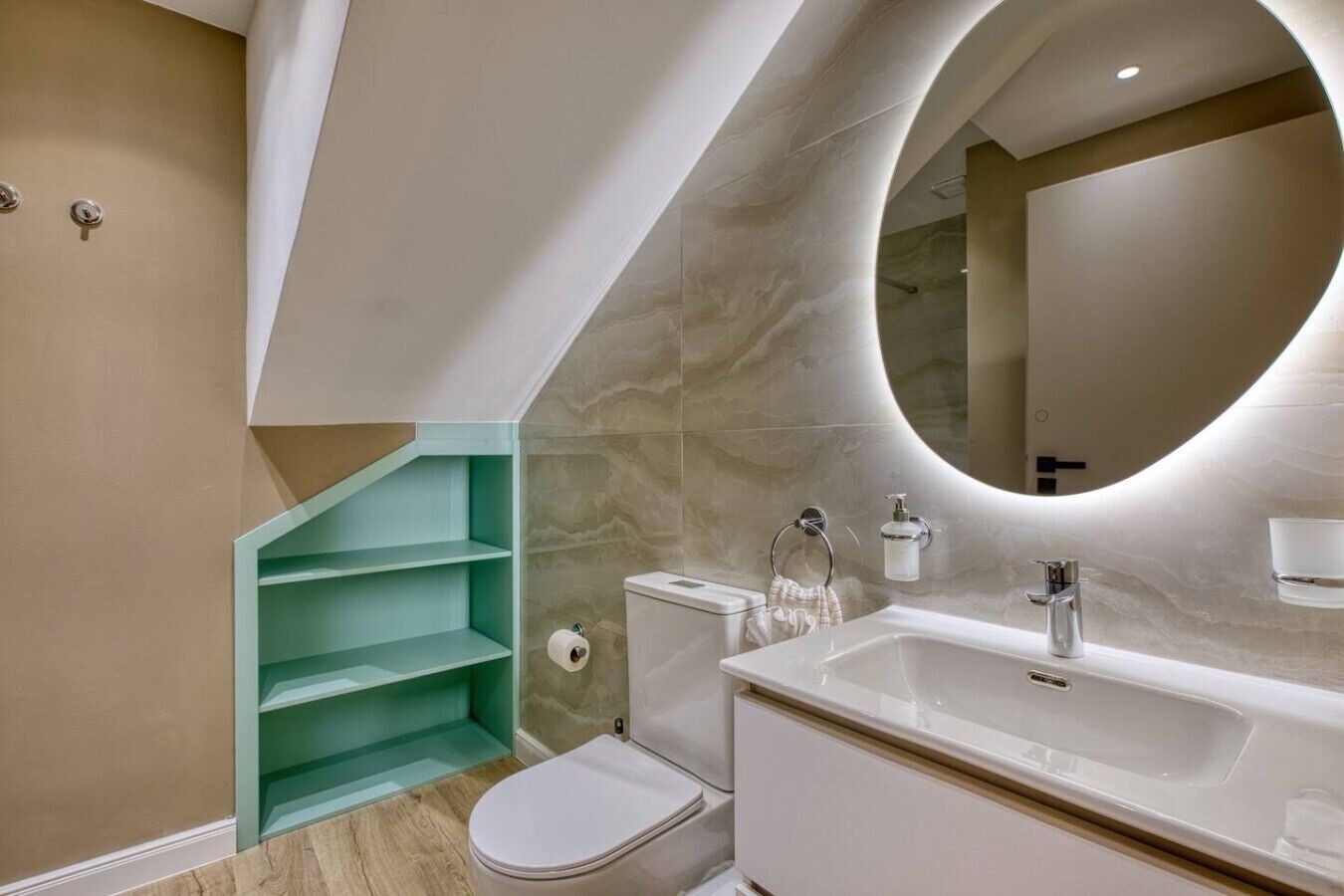 A modern bathroom with a toilet, sink, and a unique teal shelving unit.