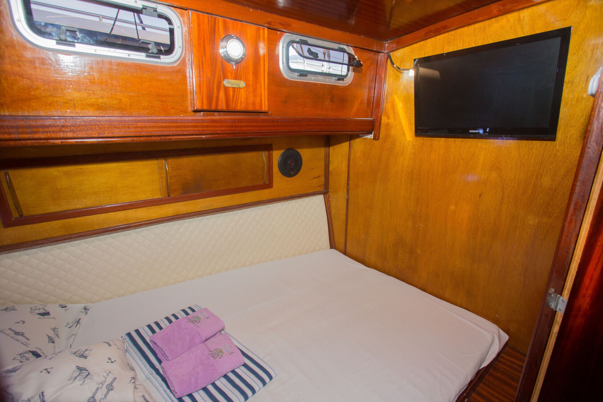 A compact, wooden interior with a bed, a small window, and a television.