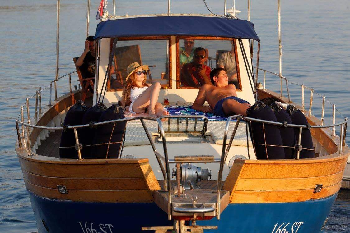 A boat with a cabin, passengers, and a blue and wooden exterior.